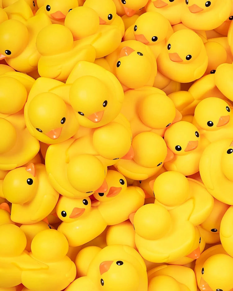 Pile of bright yellow rubber ducks with orange beaks and black eyes, pop culture collectible image