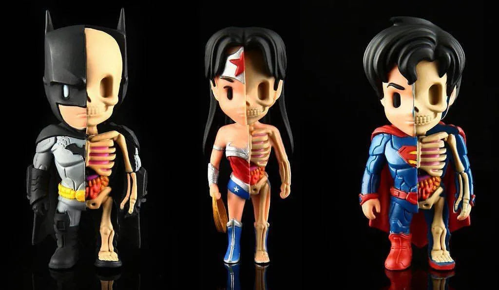 Three pop art fusion figurines of Batman, Wonder Woman, and Superman with half of their bodies showing detailed skeletons