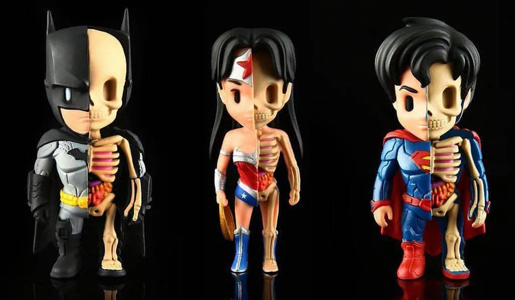 Three pop art fusion figurines of Batman, Wonder Woman, and Superman with half of their bodies showing detailed skeletons